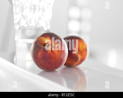 Peaches on glossy white surface Stock Photo