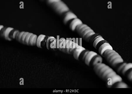 Fragment of a wooden necklace on a dark background close up. Black and white Stock Photo
