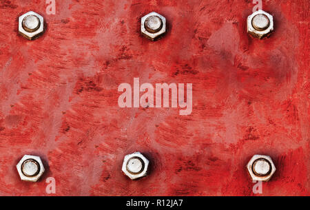 Red metal plate painted with light red and grey colours and fixed with six large steel bolt screws in parallel lines as texture background. Stock Photo