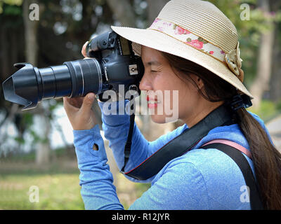 Female Vietnamese professional portrait photographer takes an outdoor portrait photo with her Canon EOS 7D DSLR camera. Stock Photo