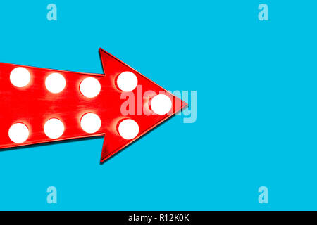 Red arrow shaped vintage colorful illuminated metallic display direction sign with glowing light bulbs pointing from left to right coming into the fra Stock Photo