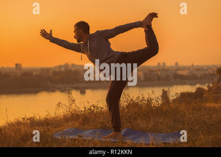 Man doing yoga on sunset with city view,Natarajasana / Shiva posture. Stock Photo