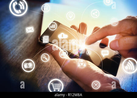 Concept of communication and internet in business with businessman with smartphone in hand at an office table and representative icons. Side view. Stock Photo