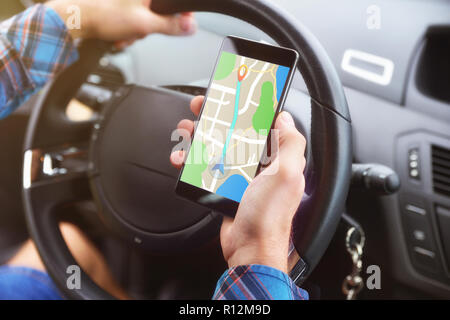 Man consulting a route on a cell phone with an application to reach his destination in a car. Stock Photo