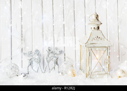 Beautiful festive background: burning candle in white lantern with Christmas ornaments in snow, with copy-space Stock Photo