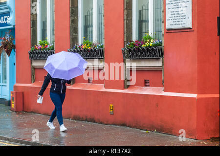 Skibbereen, West Cork, Ireland. 9th Nov, 2018. A shopper braves the elements in Skibbereen.  This afternoon will see a continuation of strong winds, which will reach gale force on the coasts. Highs today of 9 to 13°C. Credit: Andy Gibson/Alamy Live News. Stock Photo