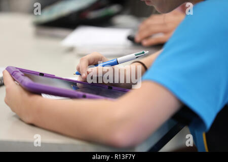Student using a purple tablet digital information technology tool devise to reseach during class time lesson at a modern high school education educati Stock Photo