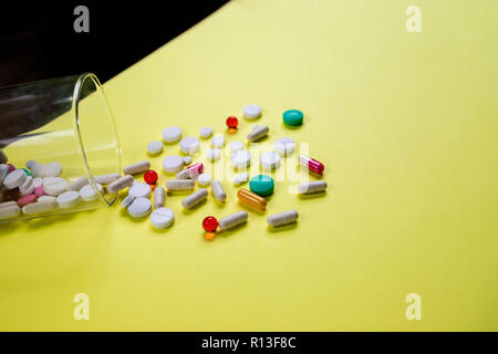 Vitamins supplements in bottle on yellow table.pills medicine and capsule pills medicine, antibiotics out of glass.Multi Vitamin complex,Diet .Multi colored nutritional supplements isolated.Copy space Stock Photo