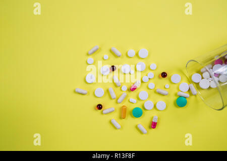 Vitamins supplements in bottle on yellow table.pills medicine and capsule pills medicine, antibiotics out of glass.Multi Vitamin complex,Diet .Multi colored nutritional supplements isolated.Copy space Stock Photo