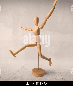 A wooden mannequin in a ballet pose, on it's base, on a white