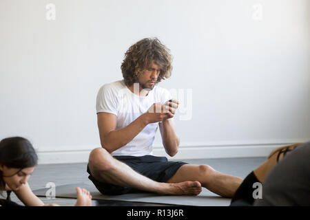 Young man sitting texting a message using his mobile phone Stock Photo