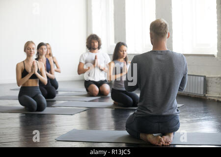 Group of sporty people in vajrasana exercise with instructor Stock Photo