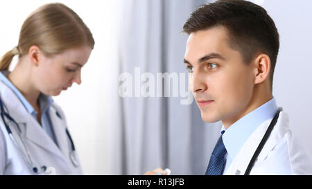 Doctors writing papers using clipboard. Physicians discussing medication program or studying at medical conference. Healthcare, insurance and medicine concept Stock Photo