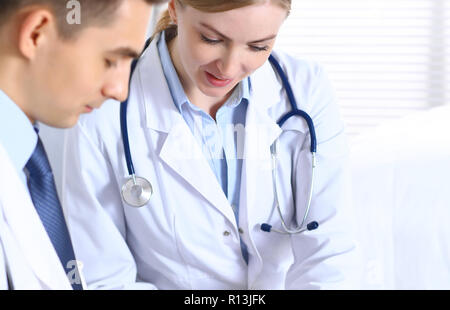 Doctors writing papers using clipboard. Physicians discussing medication program or studying at medical conference. Healthcare, insurance and medicine concept Stock Photo