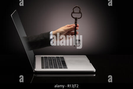 Hand with huge vintage key coming out of a laptop with sparkling effects  Stock Photo