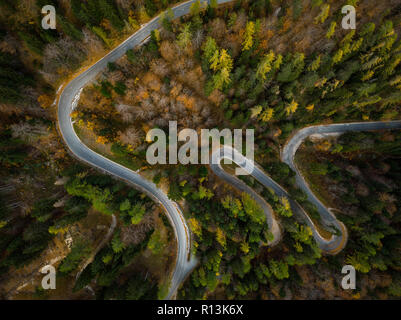 Winding road in mountains, fall woodlands, drone view from above. Stock Photo