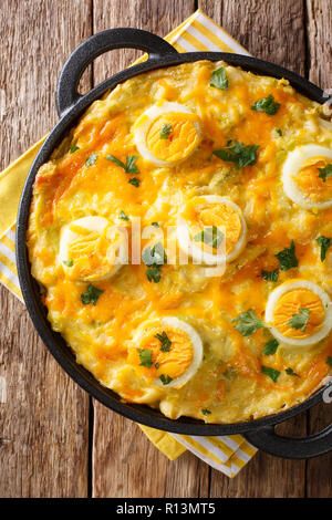 Welsh casserole Anglesey eggs baked with mashed potatoes, cheese sauce with leek close-up on the table. Vertical top view from above Stock Photo