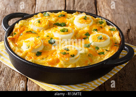 Welsh recipe Anglesey eggs made from mashed potatoes, cheese sauce leek close-up on the table. country style. Horizontal Stock Photo