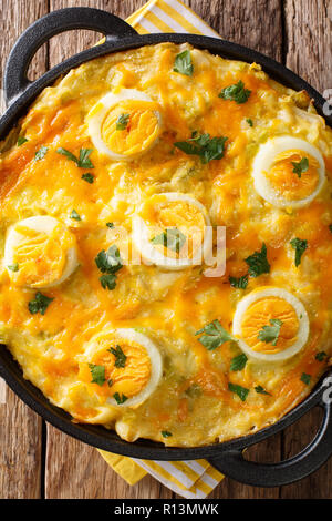 Authentic British food. Anglesey eggs baked with mashed potatoes, leek cheese sauce close-up on the table. Vertical top view from above Stock Photo