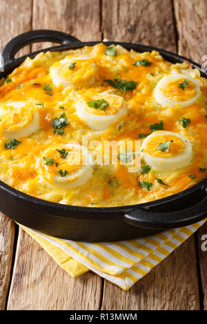 Delicious English Anglesey Eggs main course of boiled potatoes, leek cheese sauce, and eggs closeup on the table. vertical Stock Photo