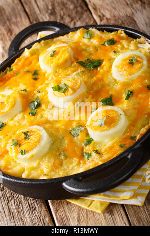 The traditional Welsh dish of Anglesey Eggs cooked from boiled potatoes, leek cheese sauce, and eggs close-up on the table. vertical Stock Photo