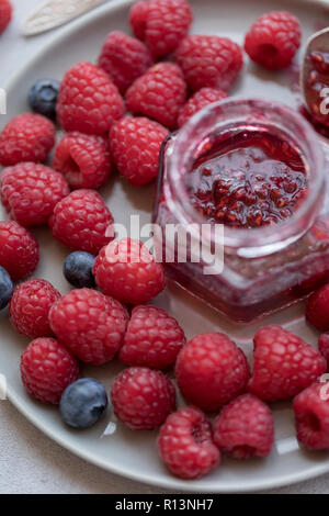 Raspberry jam in jar with berries near at gray plate Stock Photo