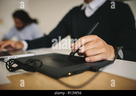 Close up of a man writing on a digital writing pad using a digital pen. Tech savvy man using modern gadget to input data. Stock Photo
