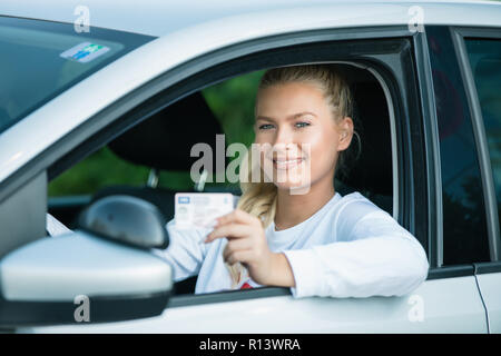 Driving school. Attractive young woman proudly showing her drivers license. Free space for text. Copy space. Stock Photo
