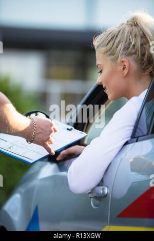 Driving school. Young woman or driving student on a driving test with her instructor. Learning to drive a car. Instructor of driving school giving exa Stock Photo