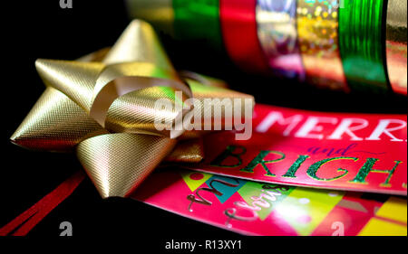 One (1) Satin Gold Christmas Bow Ribbon with Christmas Wrapping Paper and Gift Tage. Room for Copy. Stock Photo