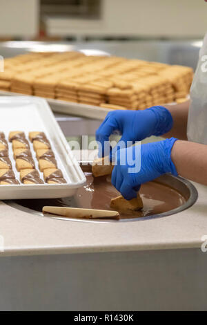 Hilo, Hawaii - Workers make Macadamia Nut Shortbread dipped in milk chocolate at Big Island Candies. Stock Photo