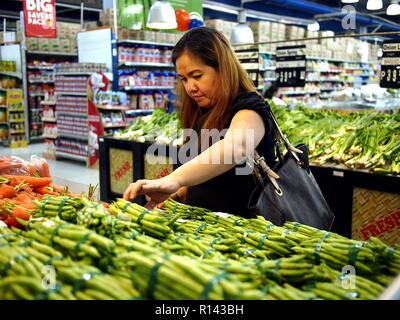 ANTIPOLO CITY, PHILIPPINES - NOVEMBER 4, 2018: A customer chooses from a bunch of fresh vegetables on sale at a supermarket. Stock Photo