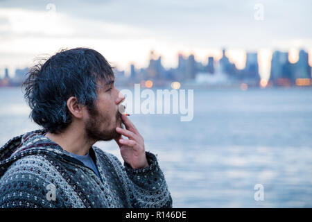 A young man smoking a joint with downtown Vancouver, BC, in the background shortly after Canadian marijuana legalization. Stock Photo