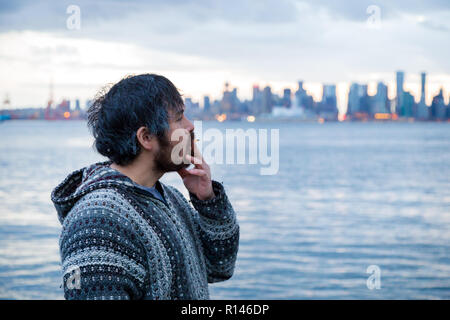 A young man smoking a joint with downtown Vancouver, BC, in the background shortly after Canadian marijuana legalization. Stock Photo