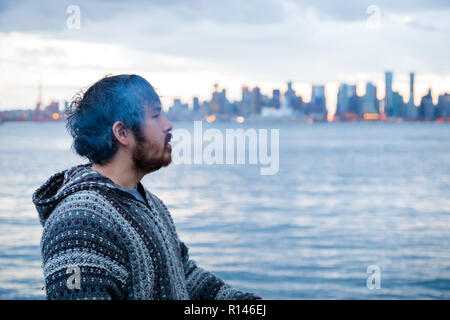 A young man smoking a joint with downtown Vancouver, BC, in the background shortly after Canadian marijuana legalization. Stock Photo