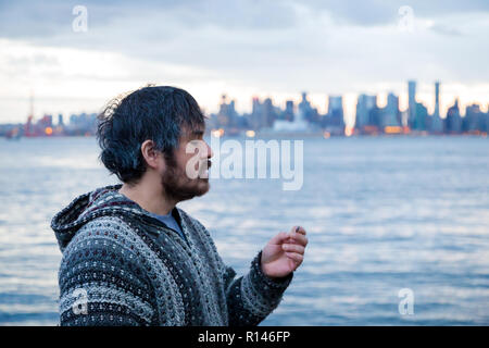 A young man smoking a joint with downtown Vancouver, BC, in the background shortly after Canadian marijuana legalization. Stock Photo