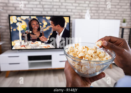 Romantic black couple with popcorn watching tv at home Stock Photo - Alamy