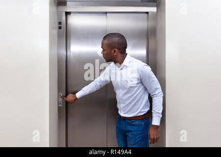Young African Man Waiting For An Elevator Pressing Button Stock Photo