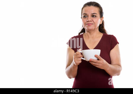 Studio shot of mature Persian woman thinking while holding coffe Stock Photo