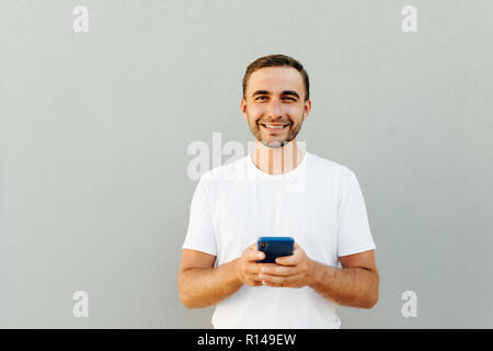 Portrait of excited using smartphone for getting sending sms isolated on gray background copy-sapce Stock Photo