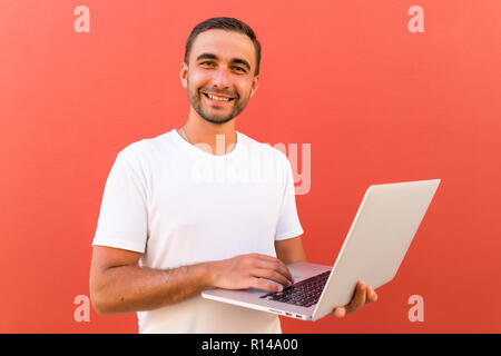 Handsome programmer with laptop on red background Stock Photo