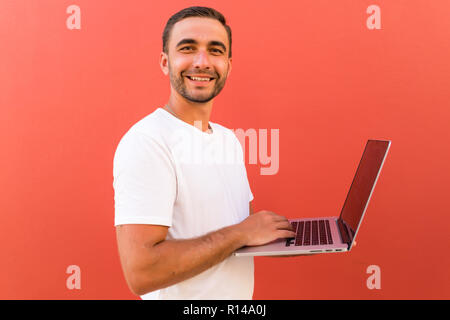 Handsome programmer with laptop on red background Stock Photo