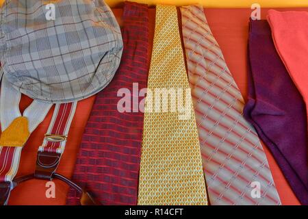Man garments. Clothing concept for men. Colorful socks, ties, braces and checked flat cap on claret background. Classical concept of men garments. Close-up Stock Photo