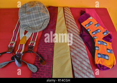 Man garments. Clothing concept for men. Colorful socks, ties, braces and checked flat cap on claret background. Classical concept of men garments. Close-up. Stock Photo