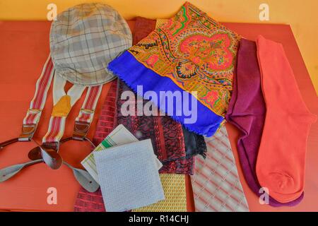 Man garments. Clothing concept for men. Colorful socks, ties, braces, scarfs and checked flat cap on claret background. Classical concept of men garments. Close-up Stock Photo