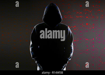 silhouette of an anonymous hacker in the hood on the background of the binary code Stock Photo