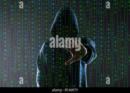 binary code on the background of the silhouette of a hacker in the hood,who hand  brush aside from the photographer, concept of cybercrime Stock Photo