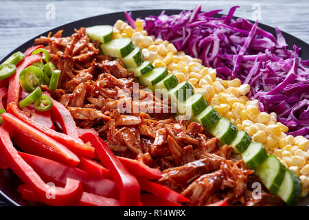 close-up of pulled pork cobb salad assembled with arranged rows of thinly sliced red cabbage, corn, sweet pepper, cucumber and chopped jalapeno on a b Stock Photo