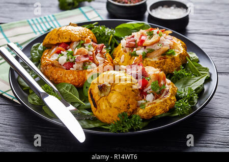 close-up of  baked squash stuffed with rice, fried chicken meat, crispy fried bacon, red bell pepper and served with spinach leaves and parsley on a b