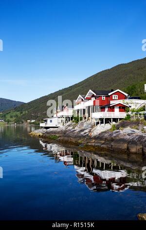 rorbuer - traditional norwegian red wooden house to stand at the lakeside and mountains in the distance, norway Stock Photo